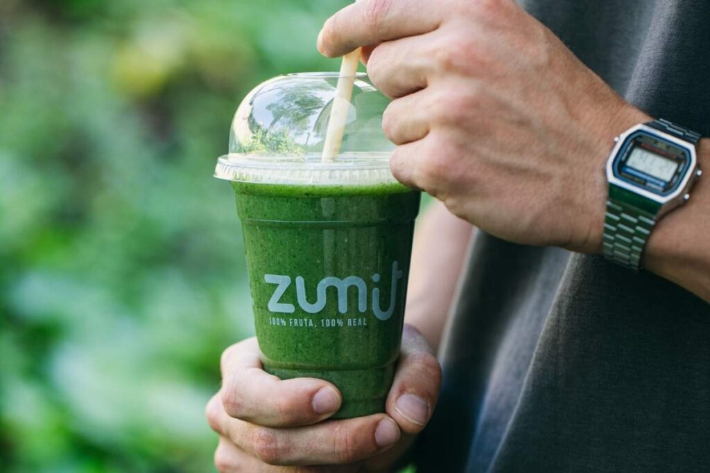Smoothie Zumit Aguacate Mix con espinaca, plátano, aguacate y lima sujetado por las manos de un hombre