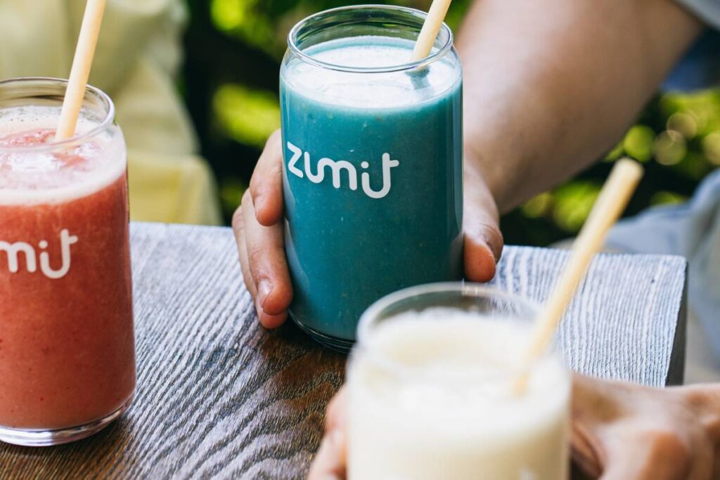 Smoothie Zumit Blue Lightning con mango, plátano, piña, melocotón, coco y espirulina azul sobre una mesa