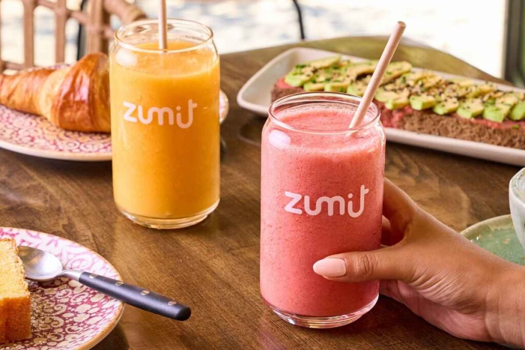 Smoothies Zumit Berries Paradise y Caribbean Passion sobre una mesa de madera en manos de personas