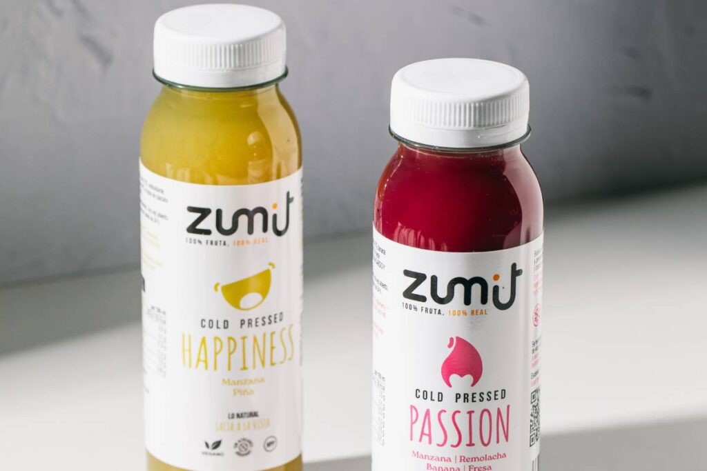 Zumos Cold Pressed Zumit Happiness y Passion, sobre una mesa.