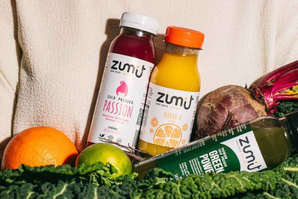 Zumos Cold Pressed Zumit Passion y de naranja, sobre una base de verduras.